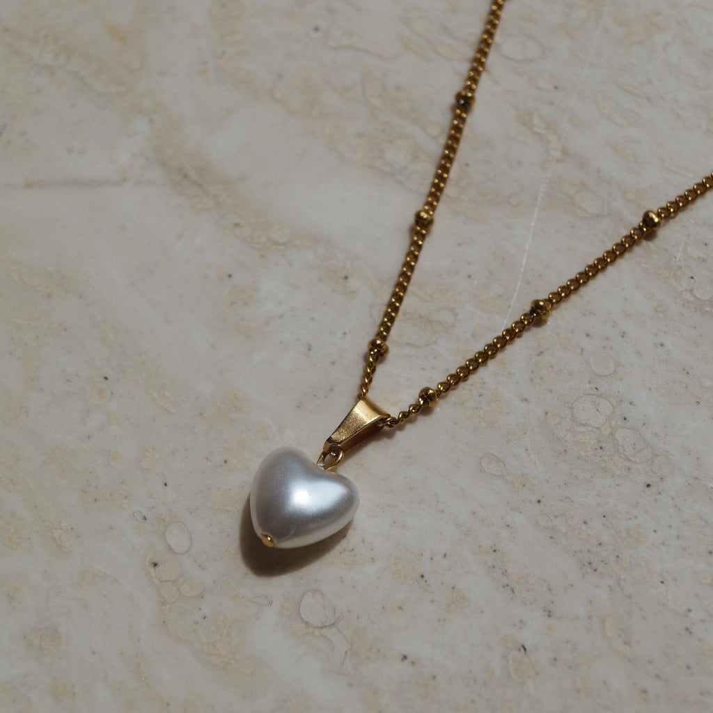 Gouden ketting met hart parel hanger, Parelhart hanger gouden ketting, Gouden hart hanger met parel, Hartvormige parelhanger op gouden ketting, Gouden parelhart sieraad, Gouden ketting met parel en hart hanger, Parel en hart hanger aan gouden ketting