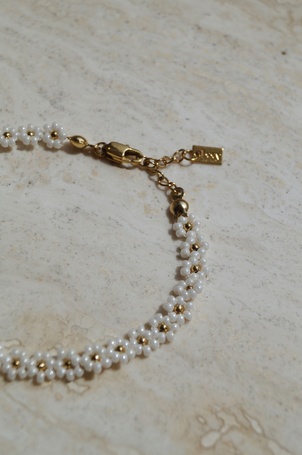 Luxe bloemen armband met gouden accenten, Stijlvolle witte gouden bloemen armband, Gouden armband met elegante bloemetjes, Wit goud armband met bloemaccent, Chique armband met witte gouden bloemen, Armband met verfijnde bloemmotieven