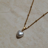 Gouden ketting met hart parel hanger, Parelhart hanger gouden ketting, Gouden hart hanger met parel, Hartvormige parelhanger op gouden ketting, Gouden parelhart sieraad, Gouden ketting met parel en hart hanger, Parel en hart hanger aan gouden ketting
