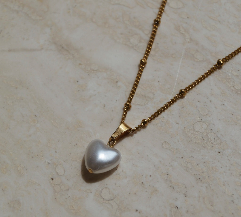 Gouden ketting met hart parel hanger, Parelhart hanger gouden ketting, Gouden hart hanger met parel, Hartvormige parelhanger op gouden ketting, Gouden parelhart sieraad, Gouden ketting met parel en hart hanger, Parel en hart hanger aan gouden ketting